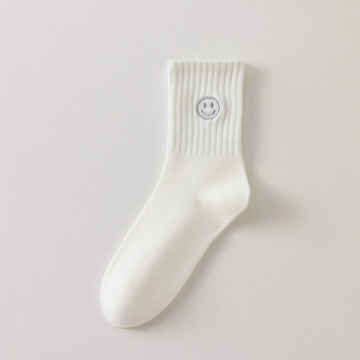 Chaussettes blanches montantes avec smiley, confortables et stylées, idéales avec des baskets. Coton épais, look tendance et maintien optimal.
