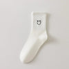 Chaussettes blanches montantes avec smiley, confortables et stylées, idéales avec des baskets. Coton épais, look tendance et maintien optimal.