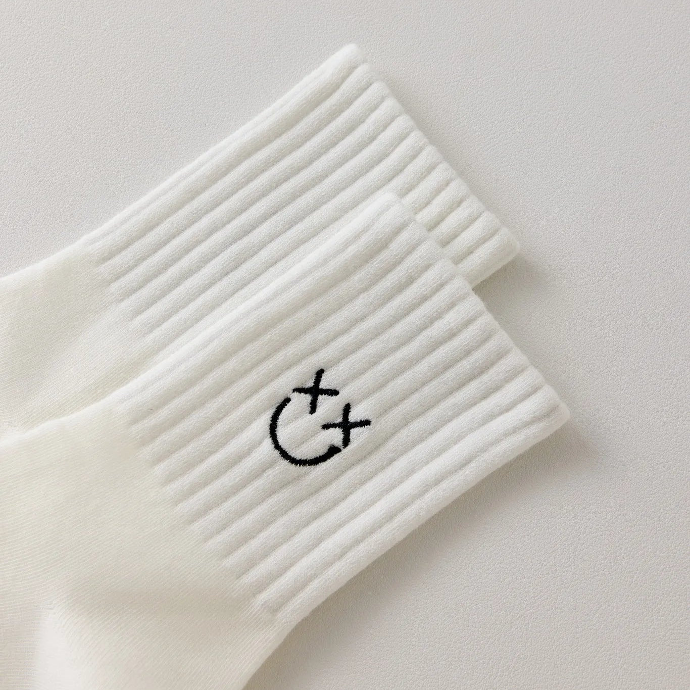 Chaussettes blanches montantes avec smiley, confortables et stylées, idéales avec des baskets. Coton épais, look tendance et maintien optimal.
