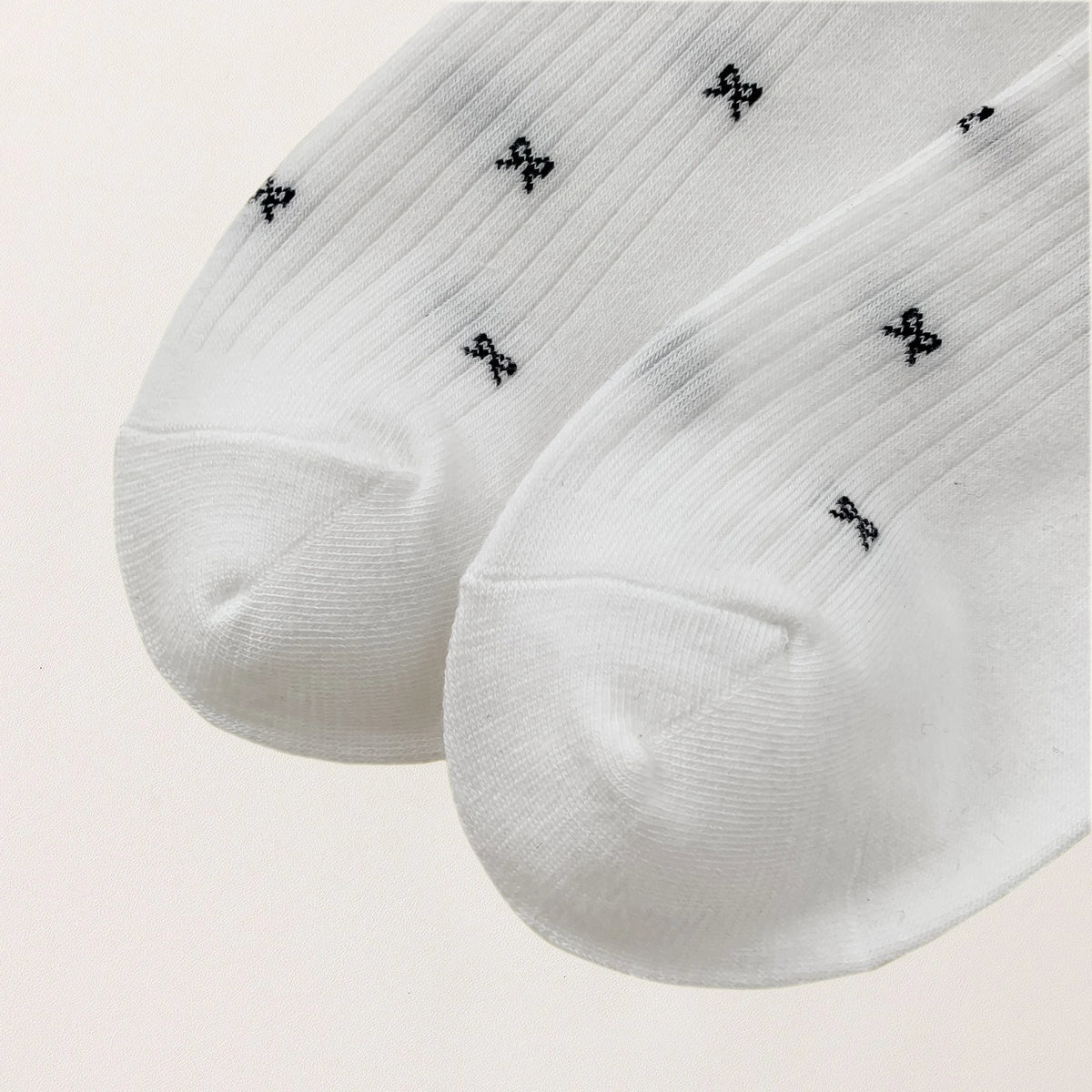 Chaussettes montantes tige côtelée. Motif petit noeud noir. Finition volant sur le haut de tige. Disponibles en blanc, gris chiné clair et noir. 