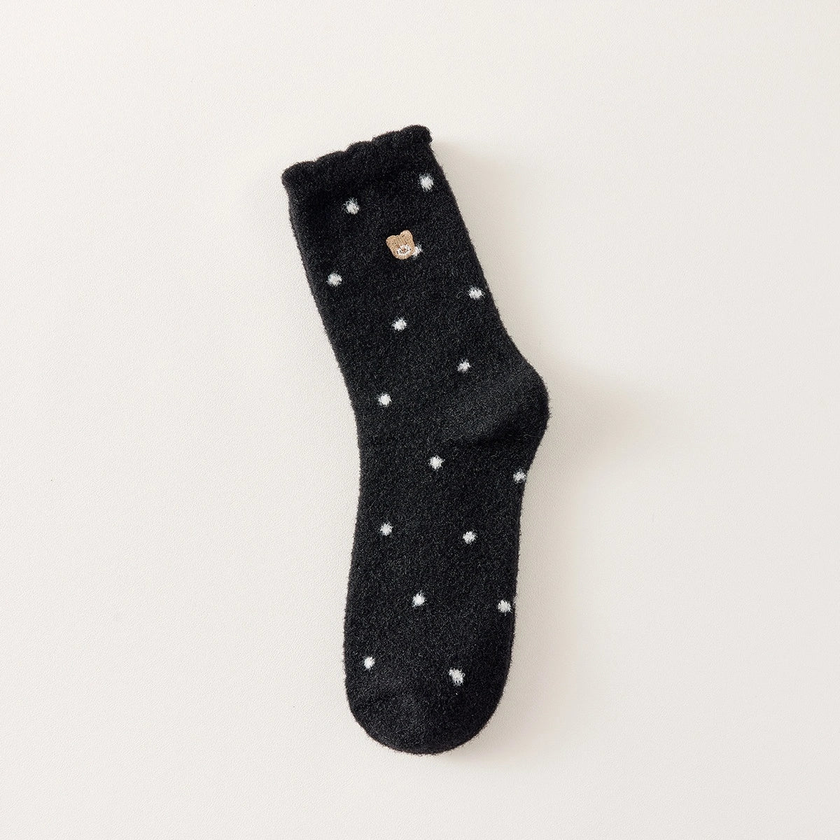 Chaussettes chaudes et douces, effet polaire, motif petits pois, tête d'ours brodée, proposée en noir et blanc cassé.