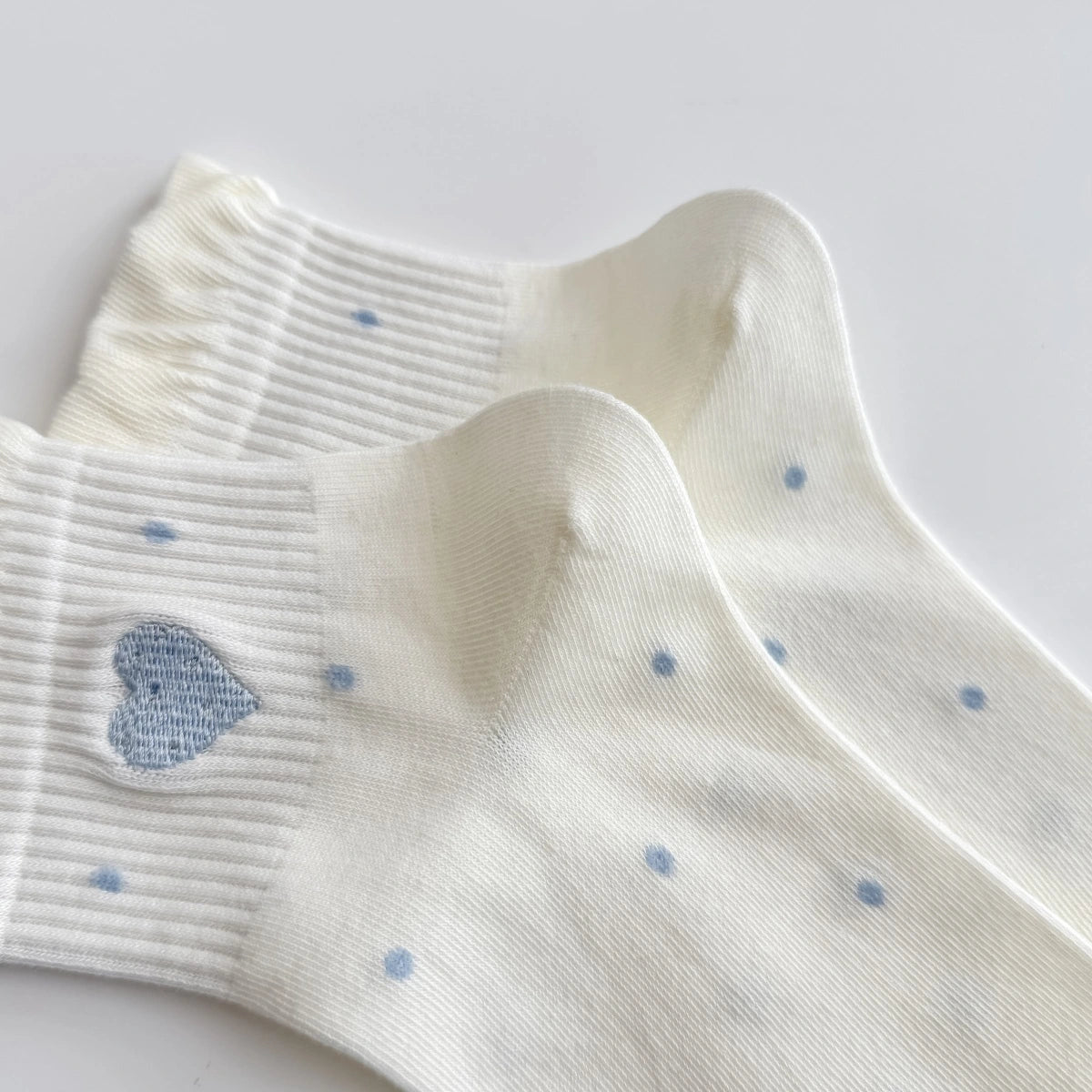 Chaussettes Volant Cœur & Pois femme vendues à l’unité. Modèles blanc à pois bleus ou gris bleu avec volant et cœur brodé. Taille unique 35-41.
