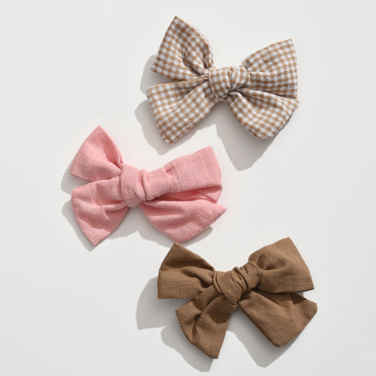Lot de 3 barrettes pince croco fille avec nœuds en tissu aux tons doux. Accessoires cheveux élégants et confortables pour bébé et enfant.