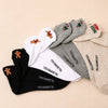 Lot de 5 chaussettes basses. Languettes brodées avec motifs de Noël : pain d'épice, sucre d'orge, teckel de Noël et message Merry Christmas (Joyeux Noël). Coloris : blanc, beige, gris chiné et noir. 