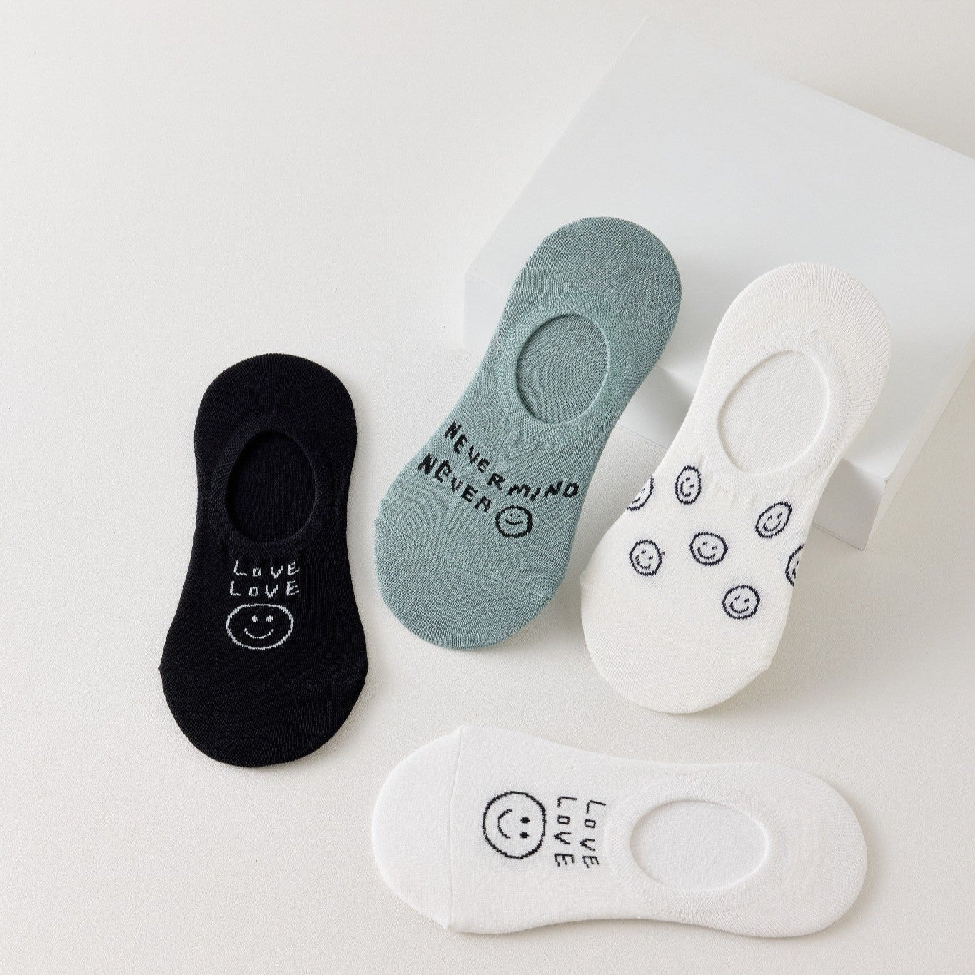 Lot de 4 socquettes invisibles en coton avec motif smiley ou message. Fond noir, blanc ou bleu. Confortables, discrètes et parfaites avec des baskets.